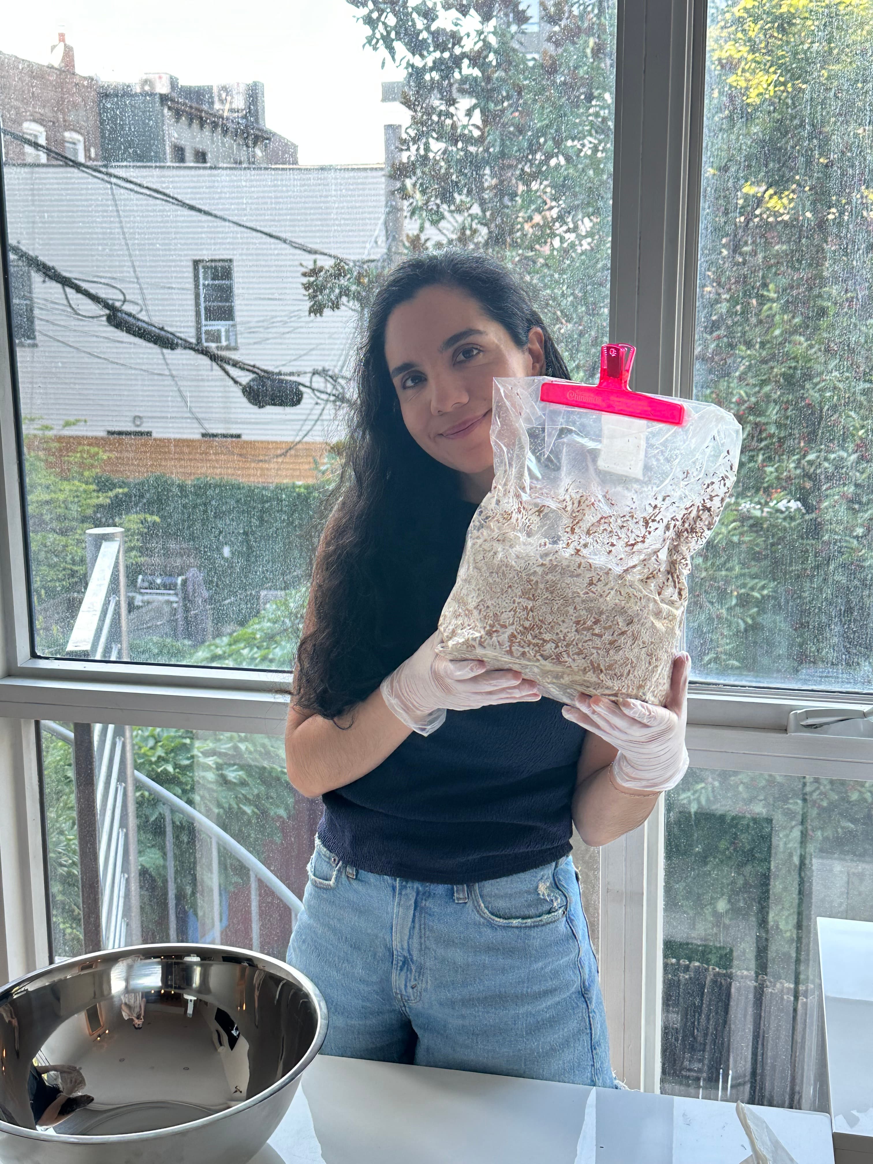 Karime Saad in the studio holding a bag of spent mushroom substrate